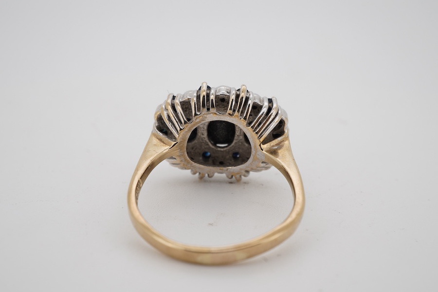 A modern 9ct gold and three stone sapphire set dress ring, with sapphire and diamond chip set border, size Q.